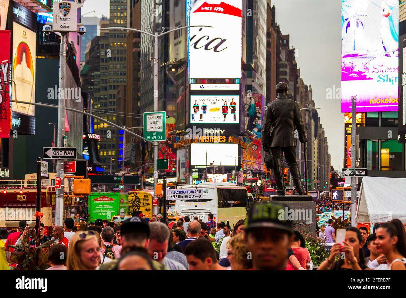 Crowds crossing the street at Times Square by the statue of Chaplain Francis P. Duffy Stock Photo