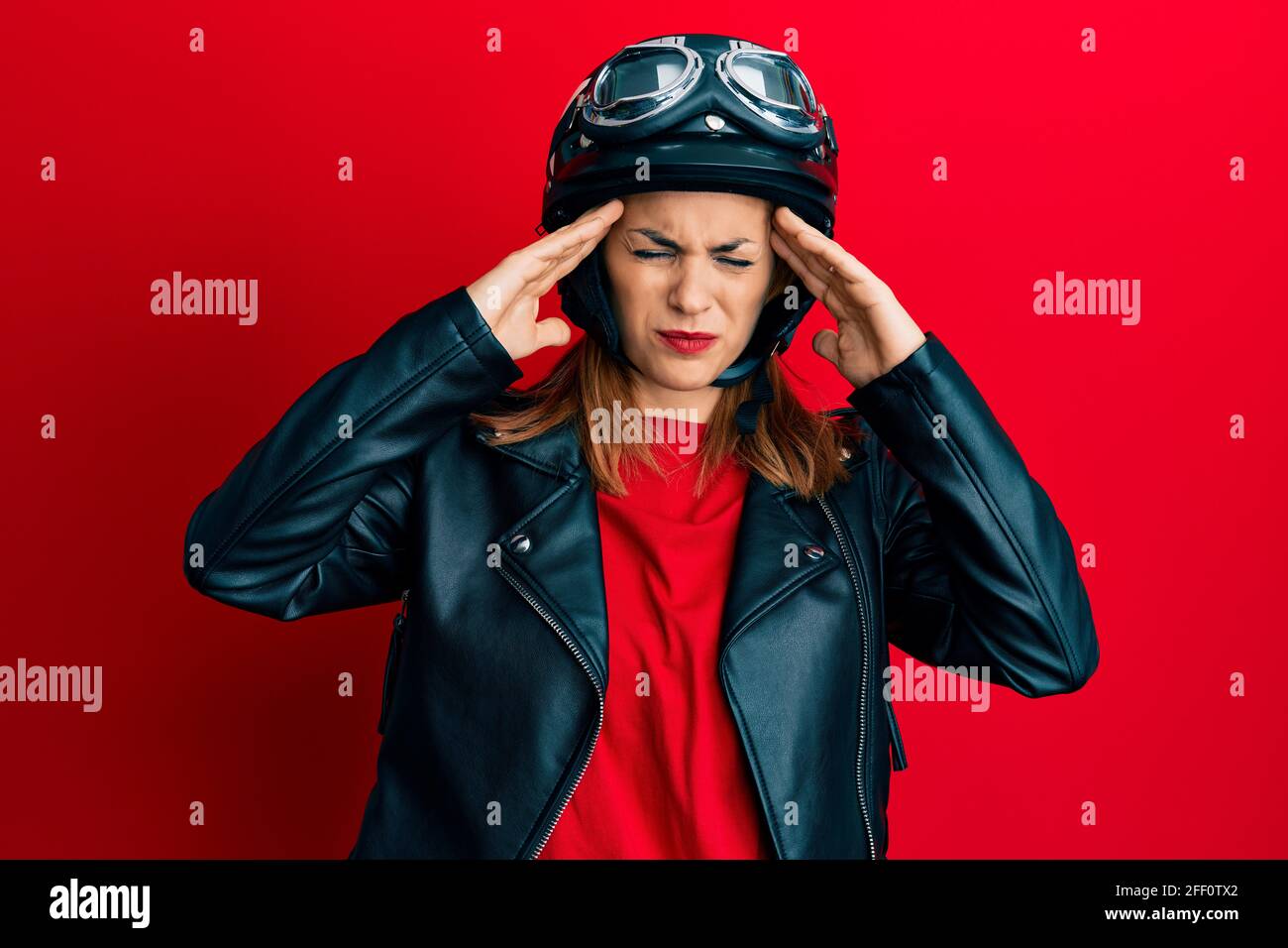 Hispanic young woman wearing motorcycle helmet suffering from headache