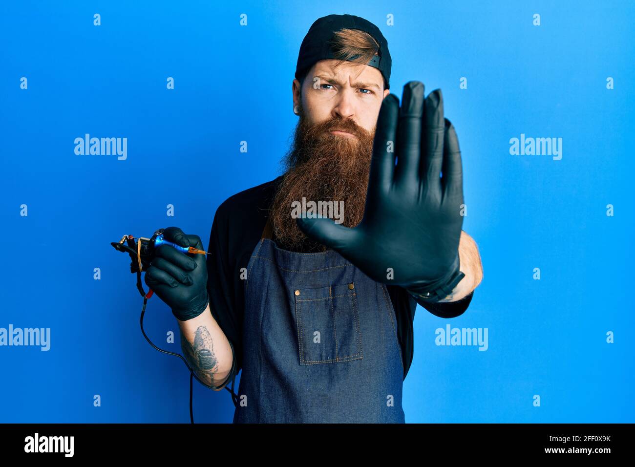 Redhead man with long beard tattoo artist wearing professional uniform and  gloves doing stop sing with palm of the hand. warning expression with negat  Stock Photo - Alamy