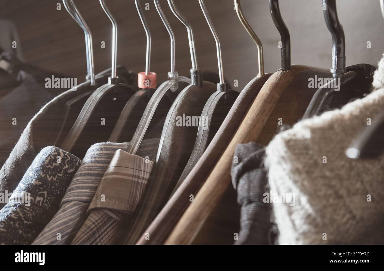 Shirts and sweaters on hangers hang on a clothes rail in the closet