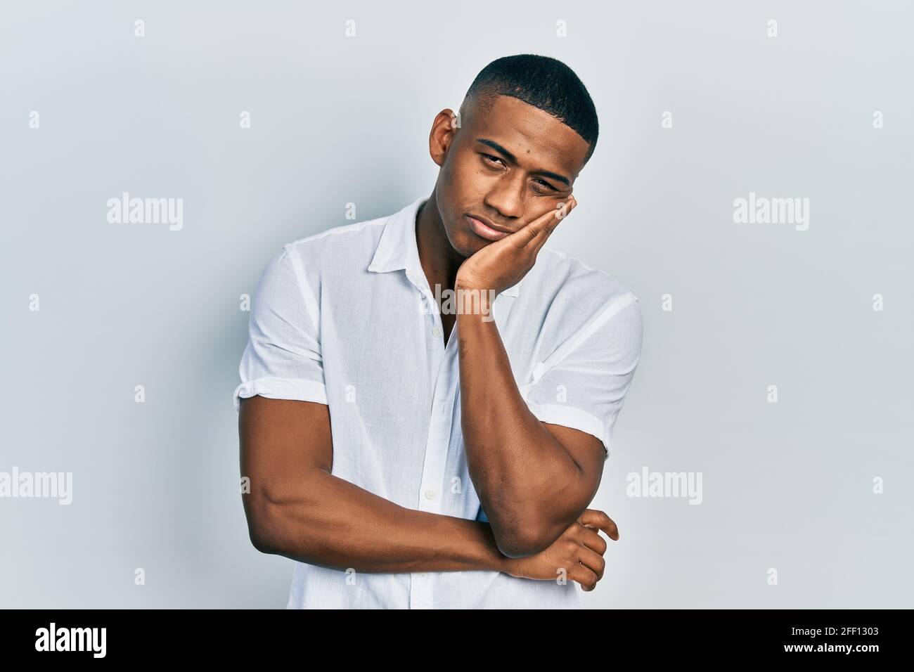 Young black man wearing casual white shirt thinking looking tired and ...