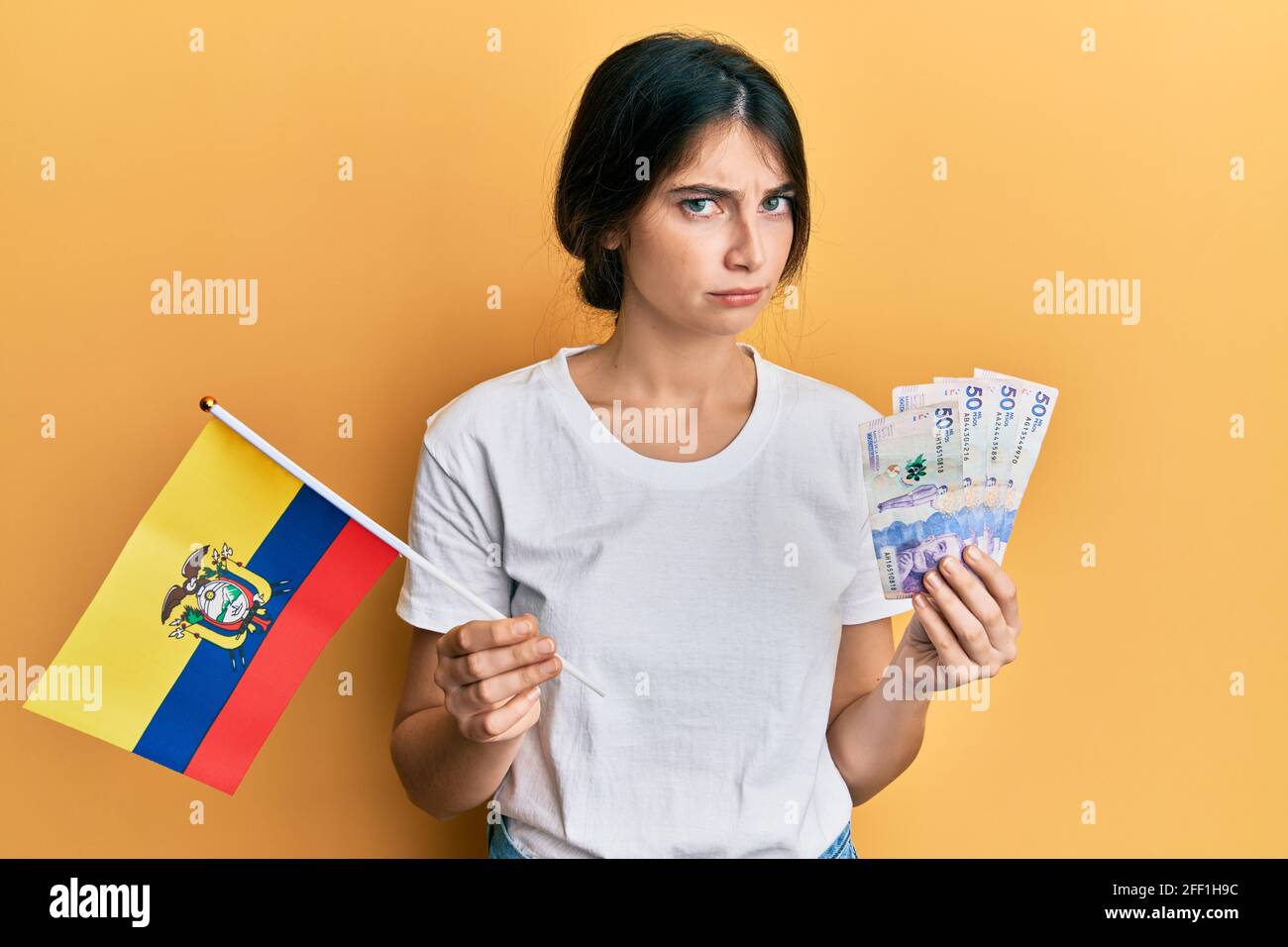 Young caucasian woman holding colombia flag and colombian pesos ...