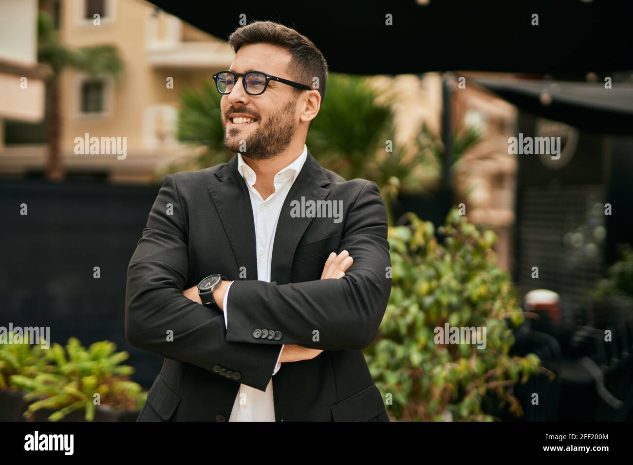 Young hispanic businessman with arms crossed smiling happy at the city ...
