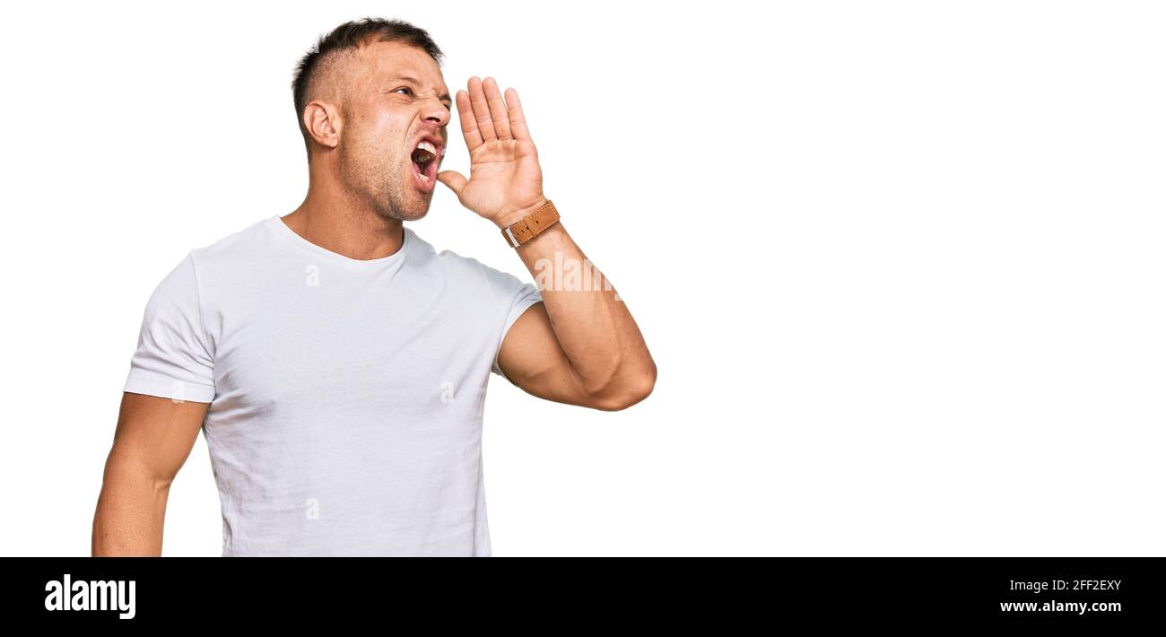 Handsome muscle man wearing casual white tshirt shouting and screaming ...