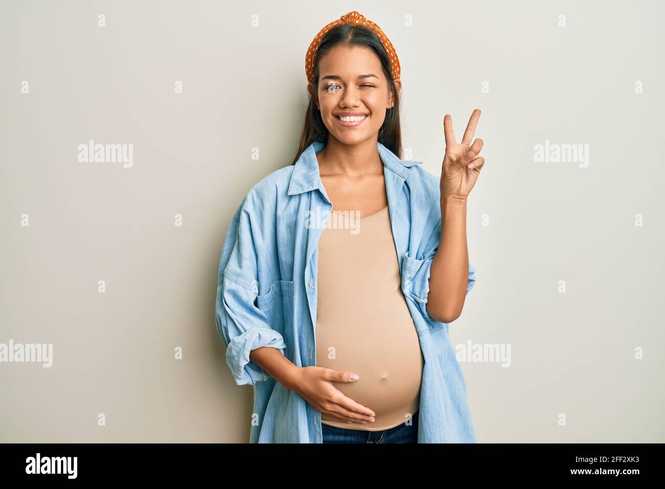 Beautiful hispanic woman expecting a baby, touching pregnant belly