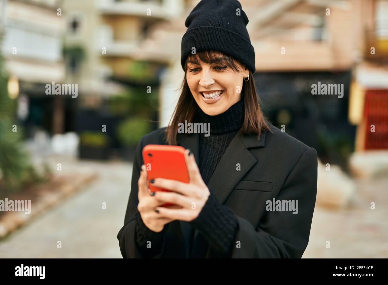 Young hispanic woman smiling happy using smartphone at the city Stock ...