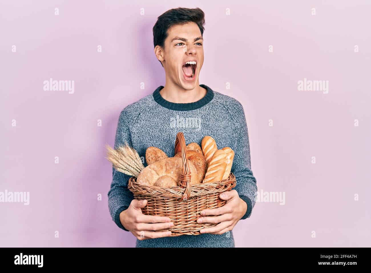 Bread Rage Young hispanic man holding wicker basket with bread angry and mad ...