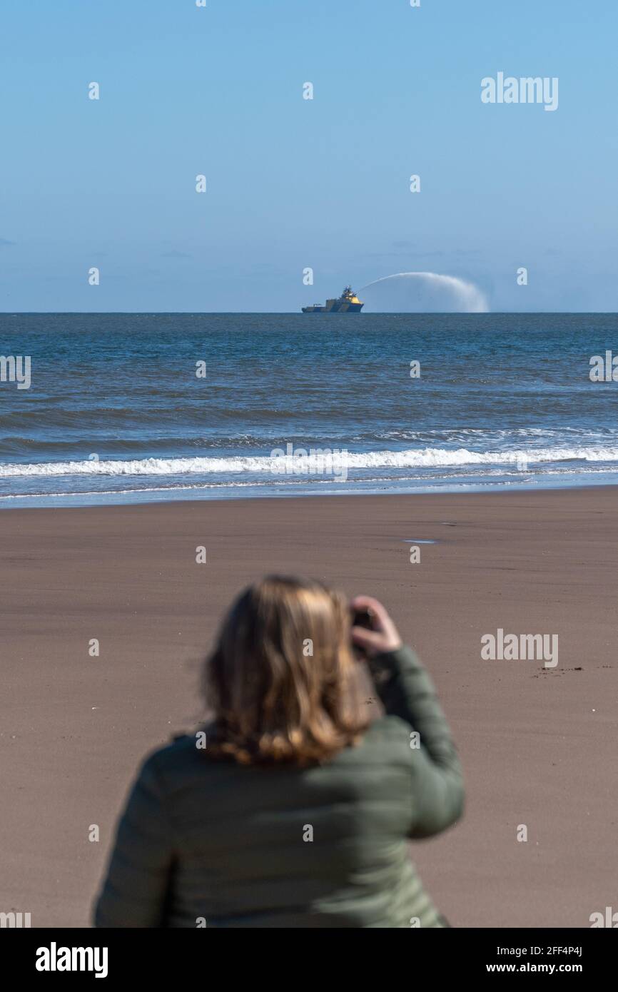 Montrose, Angus, UK. April 24 2021:  Offshore vessel and it's fast rescue craft (FRC training, prior to entering the port of Montrose, as beach walkers watch on. Credit: Barry Nixon Stable Air Media/Alamy Live News Stock Photo
