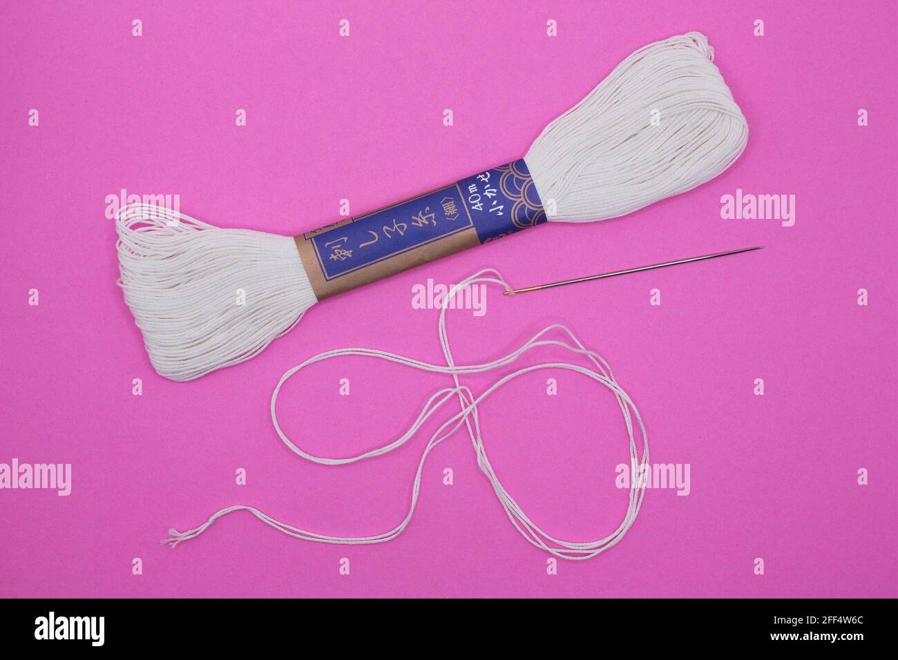 Sashiko Japanese embroidery needle and thread on a pink background