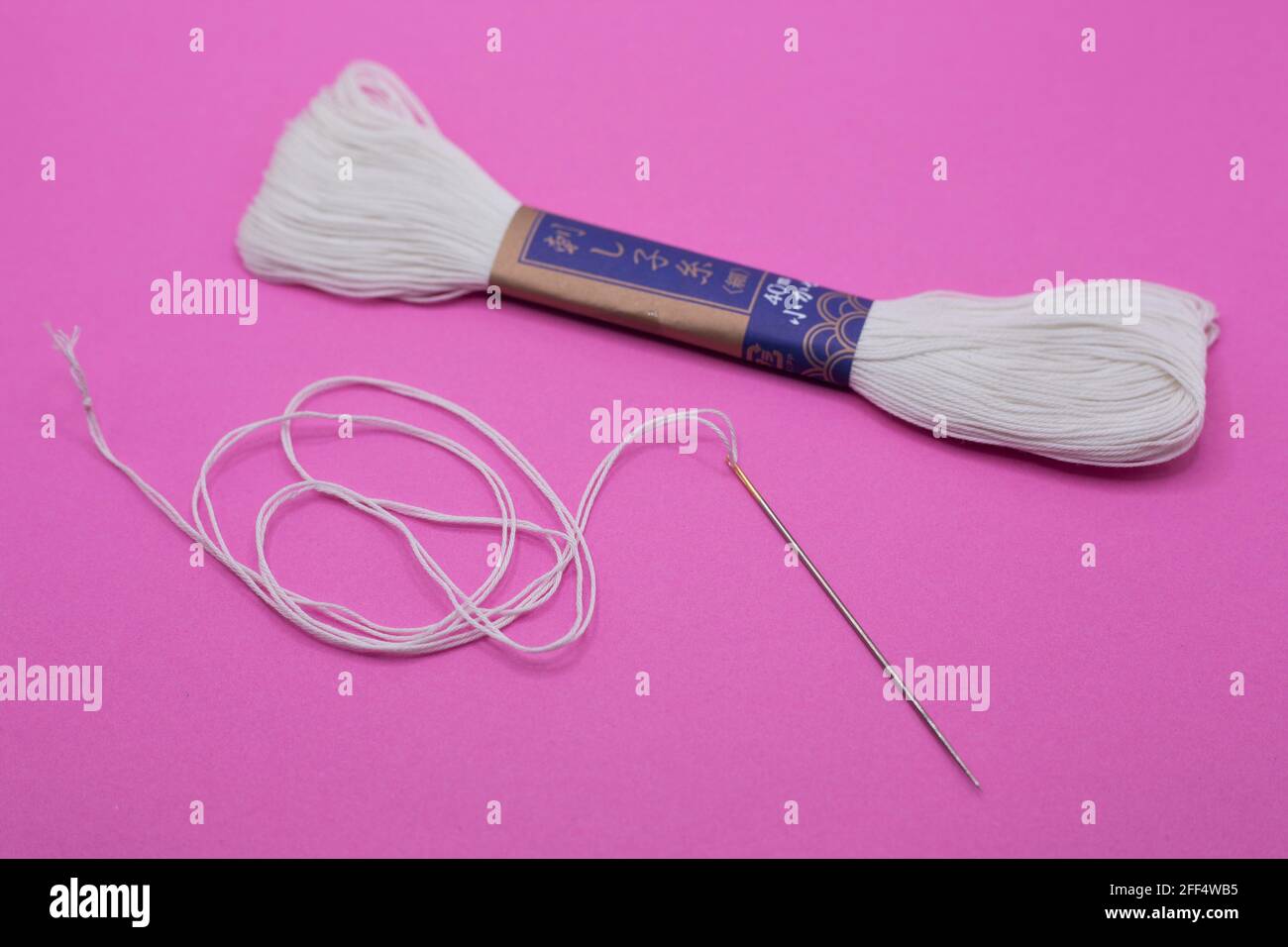 Sashiko Japanese embroidery needle and thread on a pink background