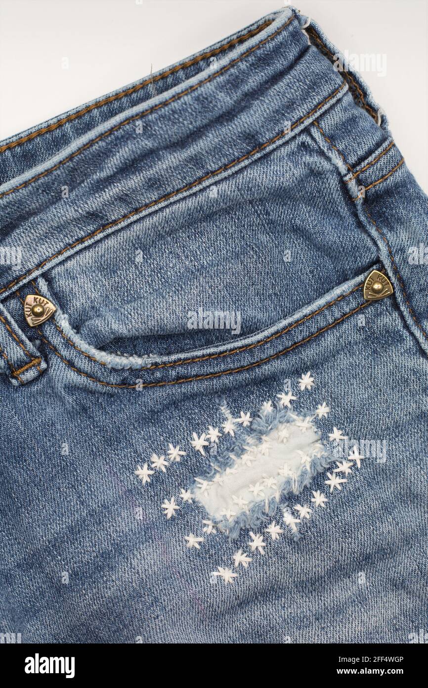 Jeans with a hole that have been sloppily mended with embroidered
