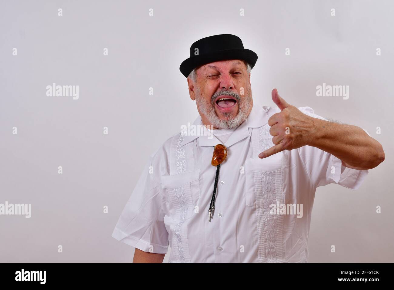 View of an elderly man making silly faces gesturing a call with his ...