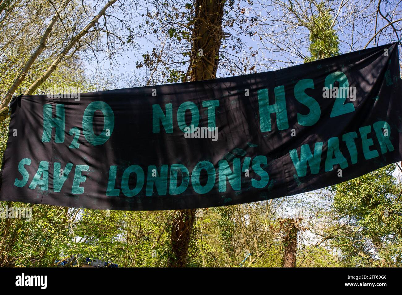 Denham, Buckinghamshire, UK. 24th April, 2021. An H2O not HS2, Save London's Water banner at the Stop HS2 protest camp in Denham Country Park. Stop HS2 activists have grave concerns about the potential risk HS2 may cause to London's drinking water by drilling into the aquifer. The High Speed Rail link from London to Birmingham puts 693 wildlife sites, 108 ancient woodlands and 33 SSSIs at risk. Credit: Maureen McLean/Alamy Stock Photo