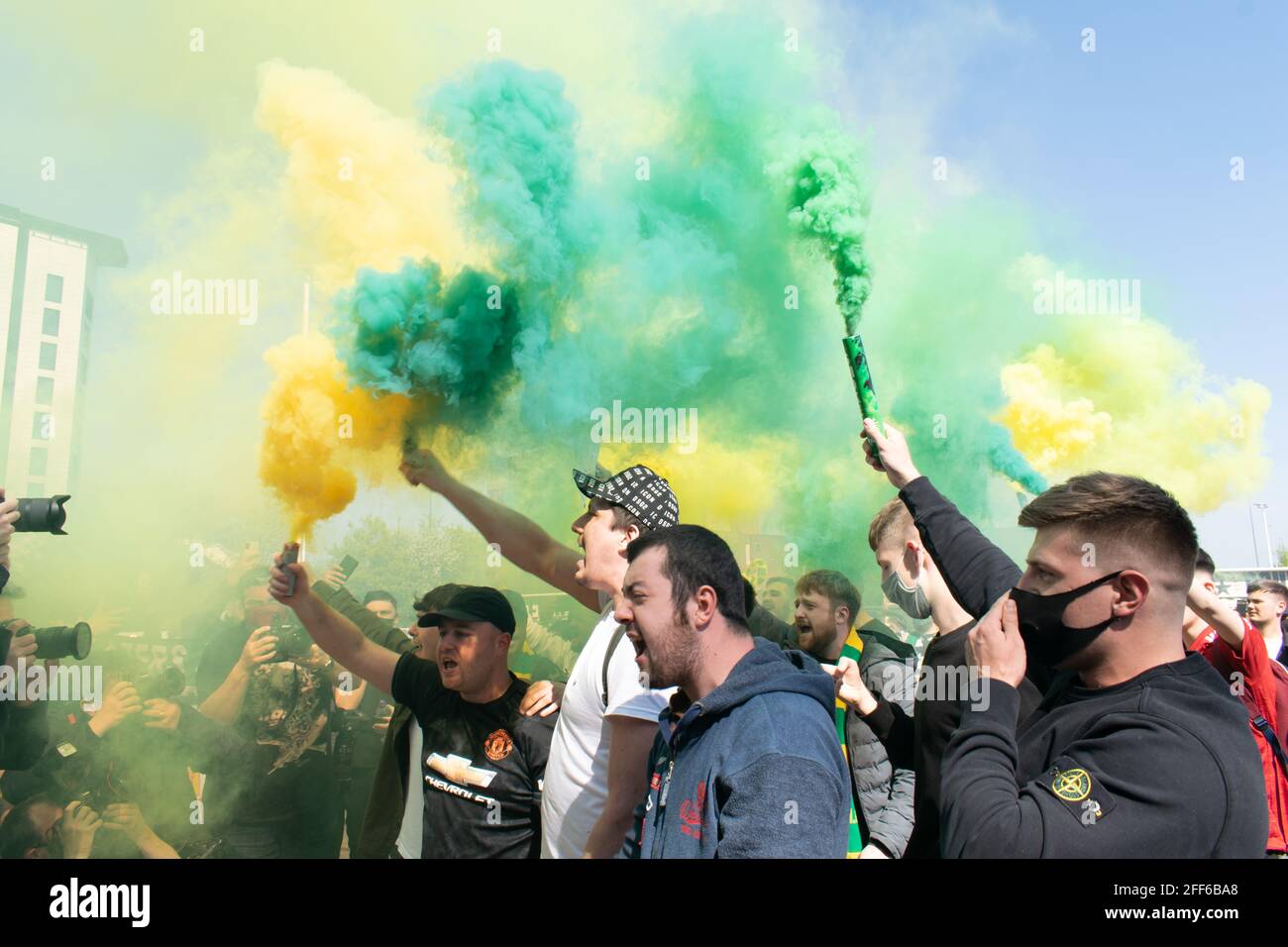Protest against Glazer at Old Trafford football ground. Supporters holding green and gold smoke flare. Manchester United stadium, UK. Stock Photo