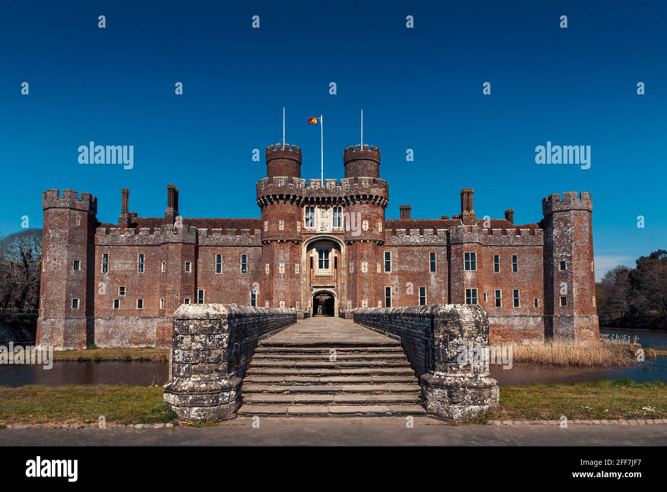 Herstmonceux Castle, East Sussex, UK. One of the oldest significant brick buildings still standing in England. Flying Queen's University (Canada) Flag Stock Photo