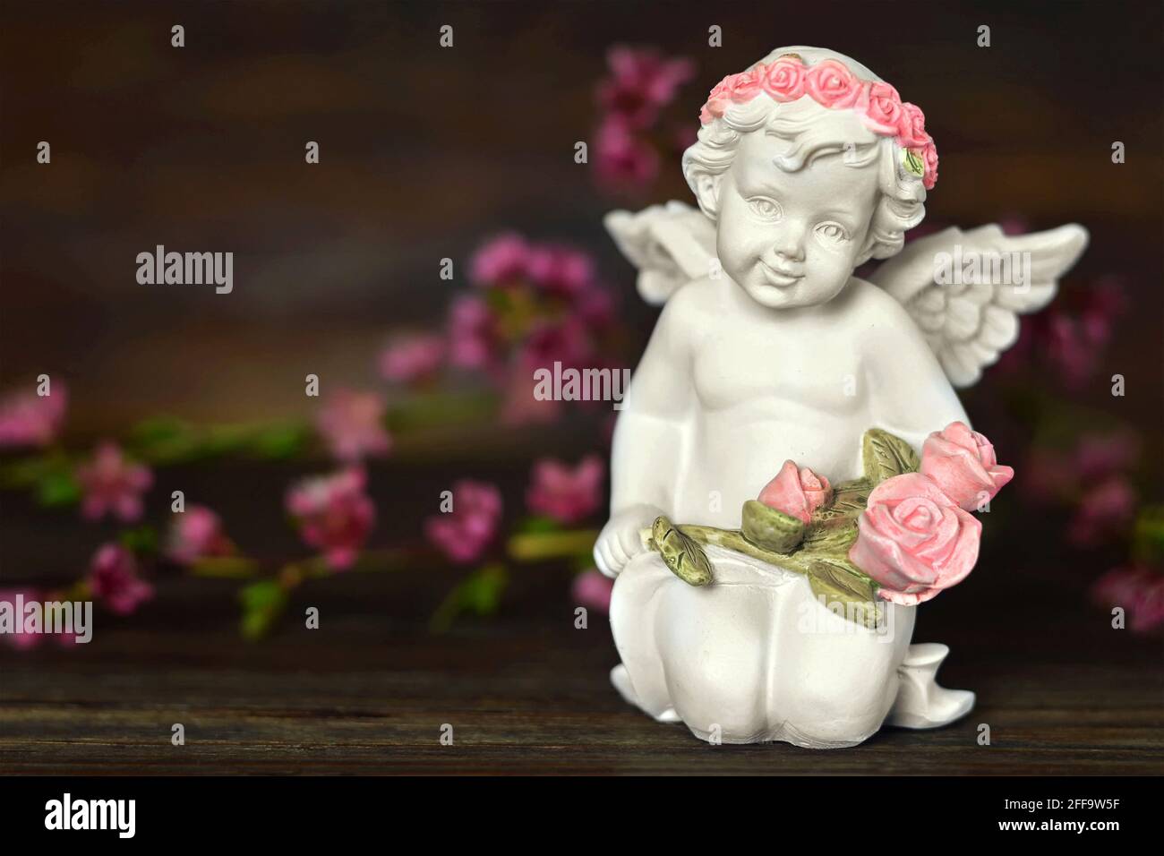 Guardian angel and spring flowers on wooden background Stock Photo