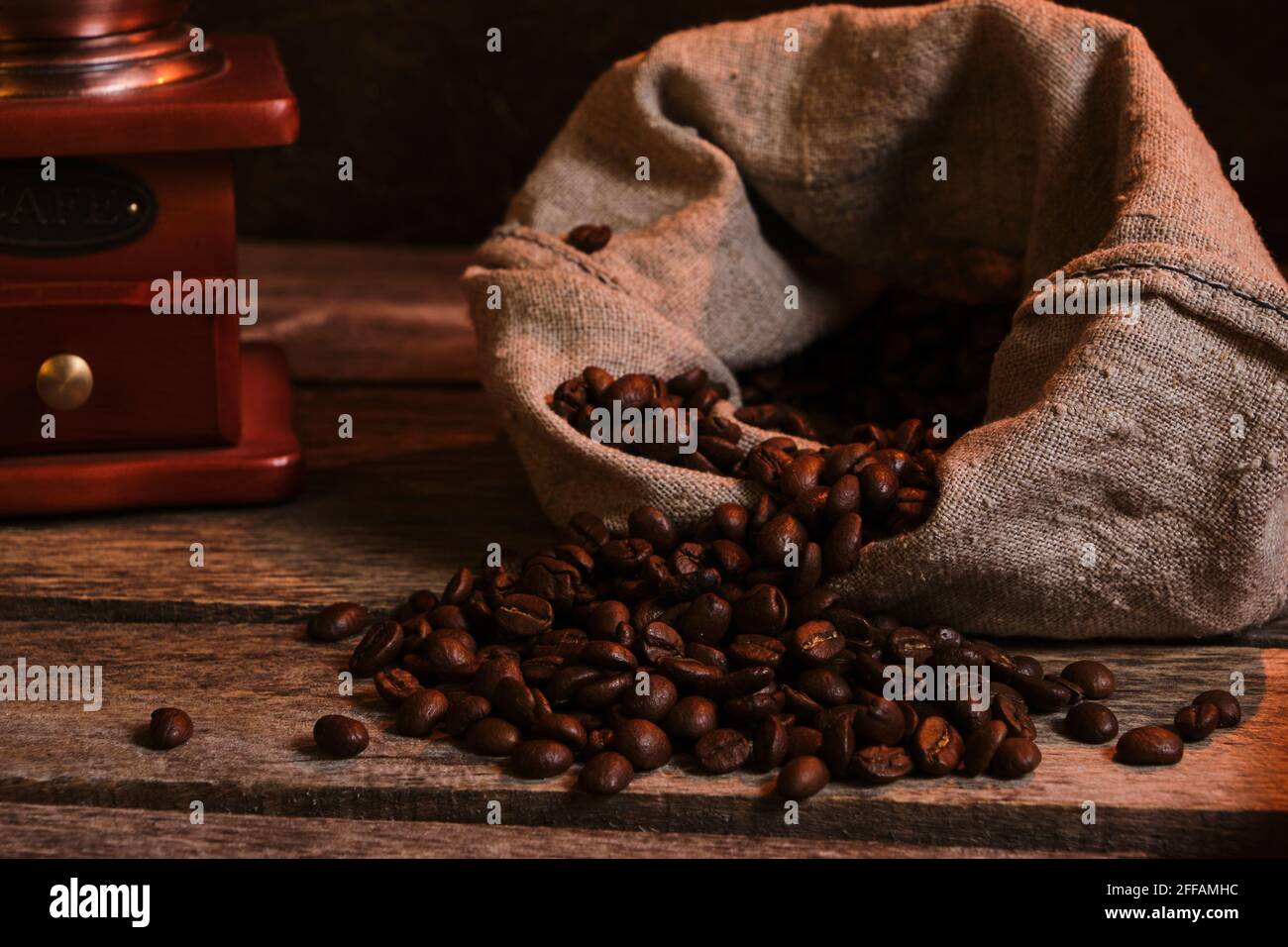 Roasted coffee beans in bag and coffee grinder on an old wooden table Stock Photo