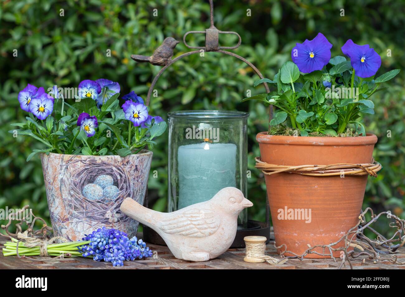 spring garden decoration with blue viola flowers and terracotta bird Stock Photo