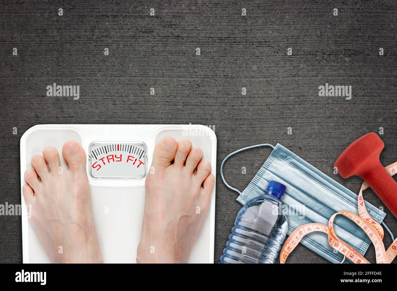 Woman on bathroom scale with Stay Fit message during COVID-19 quarantine. Concept of healthy lifestyle and sport exercise during self isolation surrou Stock Photo