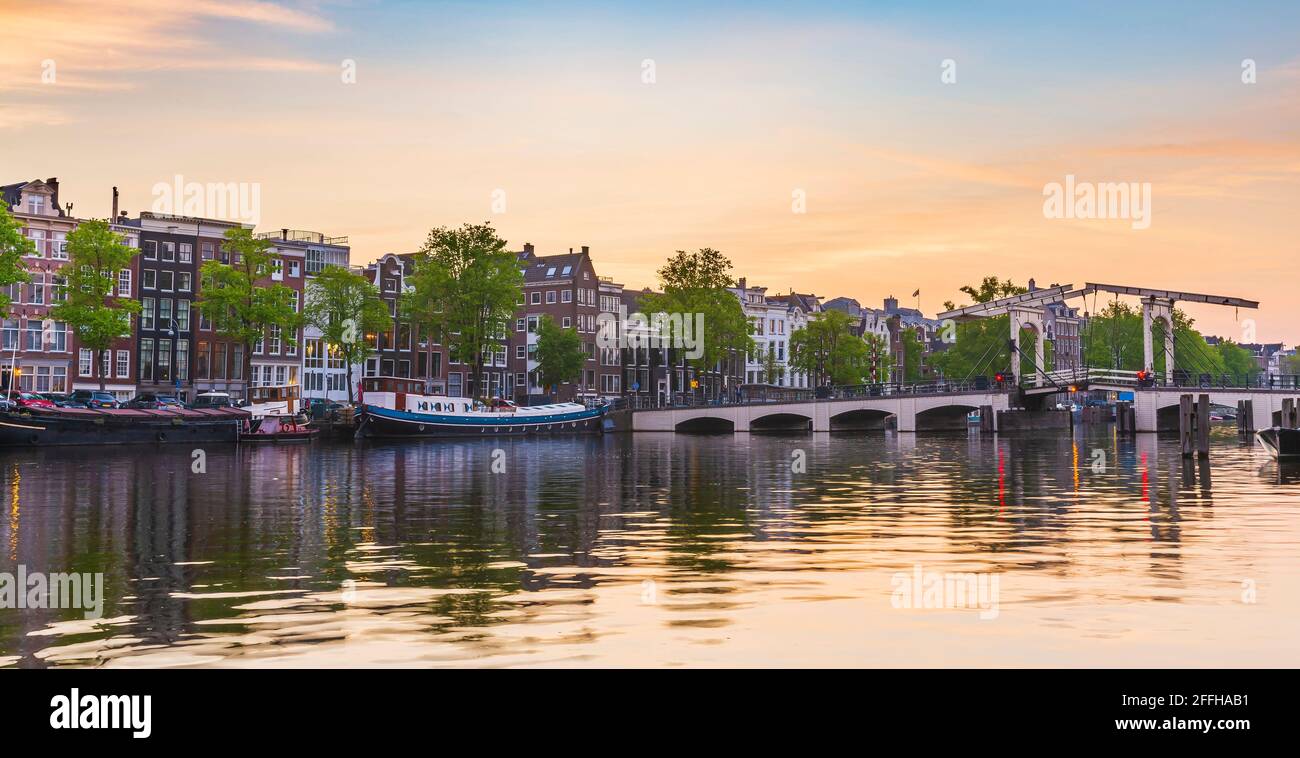 Amsterdam streets and canals during dusk. Bridges illuminated, summer season. Popular travel destination for tourists. Stock Photo