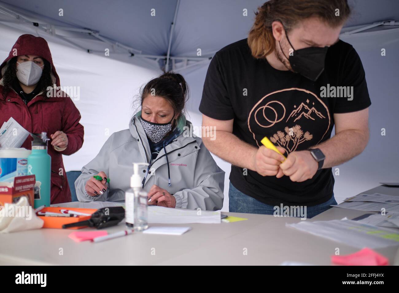 From left, Hannah Glaser, a community health advocate aids Harm Reduction  Outreach Specialist Sharon Bruns and volunteer Alex Lane as they register  people arriving at a temporary COVID-19 vaccine site organized by