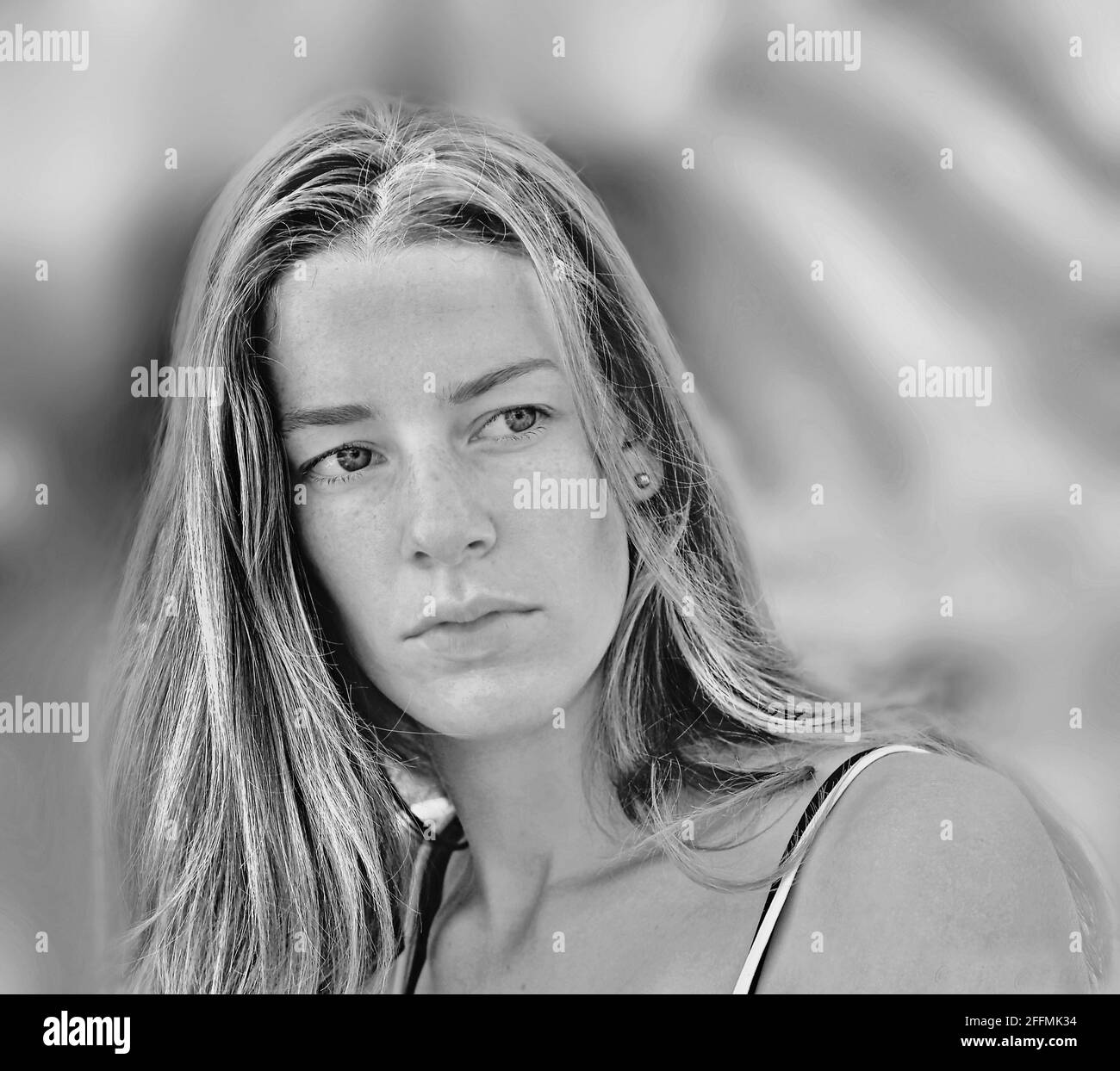 soft black and white frontal portrait of a very pretty young woman with long hair. and middle parting. She doesn't look at the camera. soft color grad Stock Photo