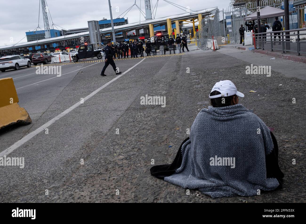 An asylum-seeking migrant sits on the ground as Central American migrants protest to demand access and asylum in the United States from U.S. President Joe Biden, at the Mexico-US San Ysidro border crossing in Tijuana, Mexico, April 23, 2021. Picture taken April 23, 2021. REUTERS/Toya Sarno Jordan Stock Photo