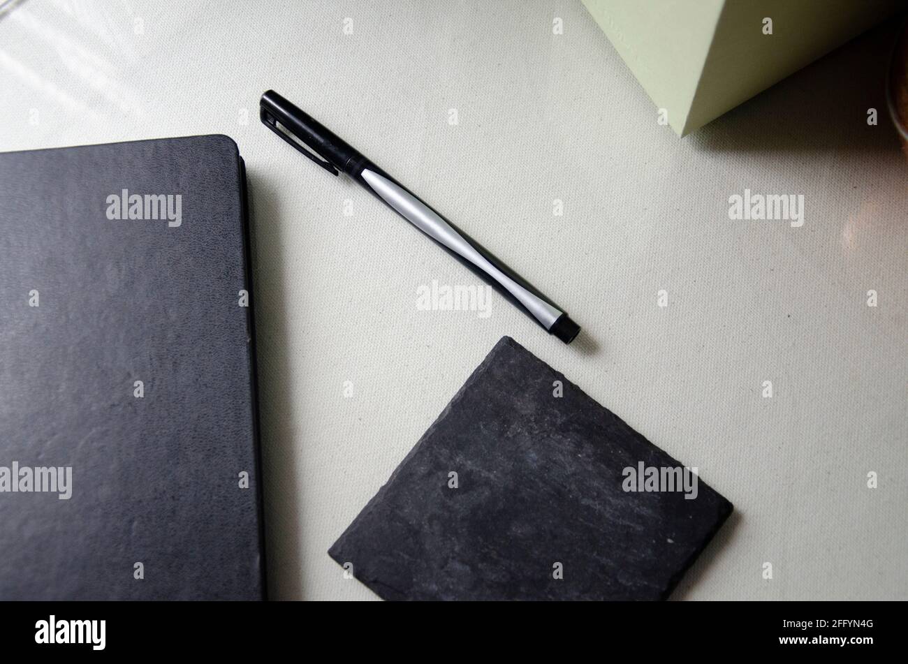Glass Desk with Black Notepad, Pen, & Coaster Set Up Stock Photo