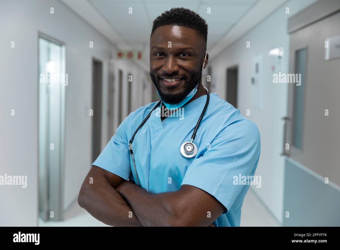 Portrait of african american male doctor wearing face mask standing in ...