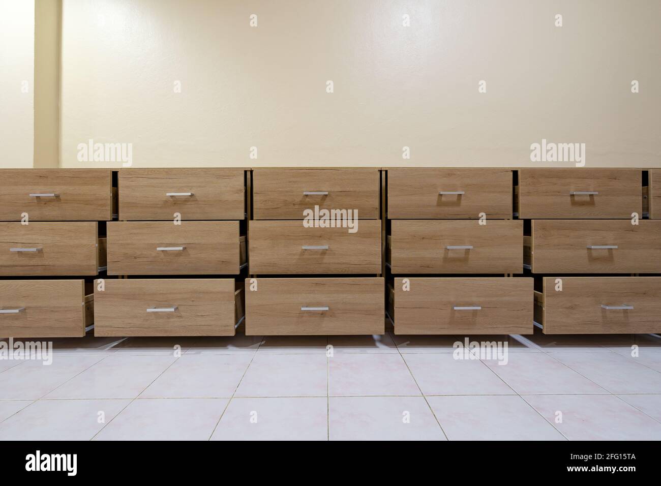 Wooden chest with open drawers against a cement wall background. Stock Photo