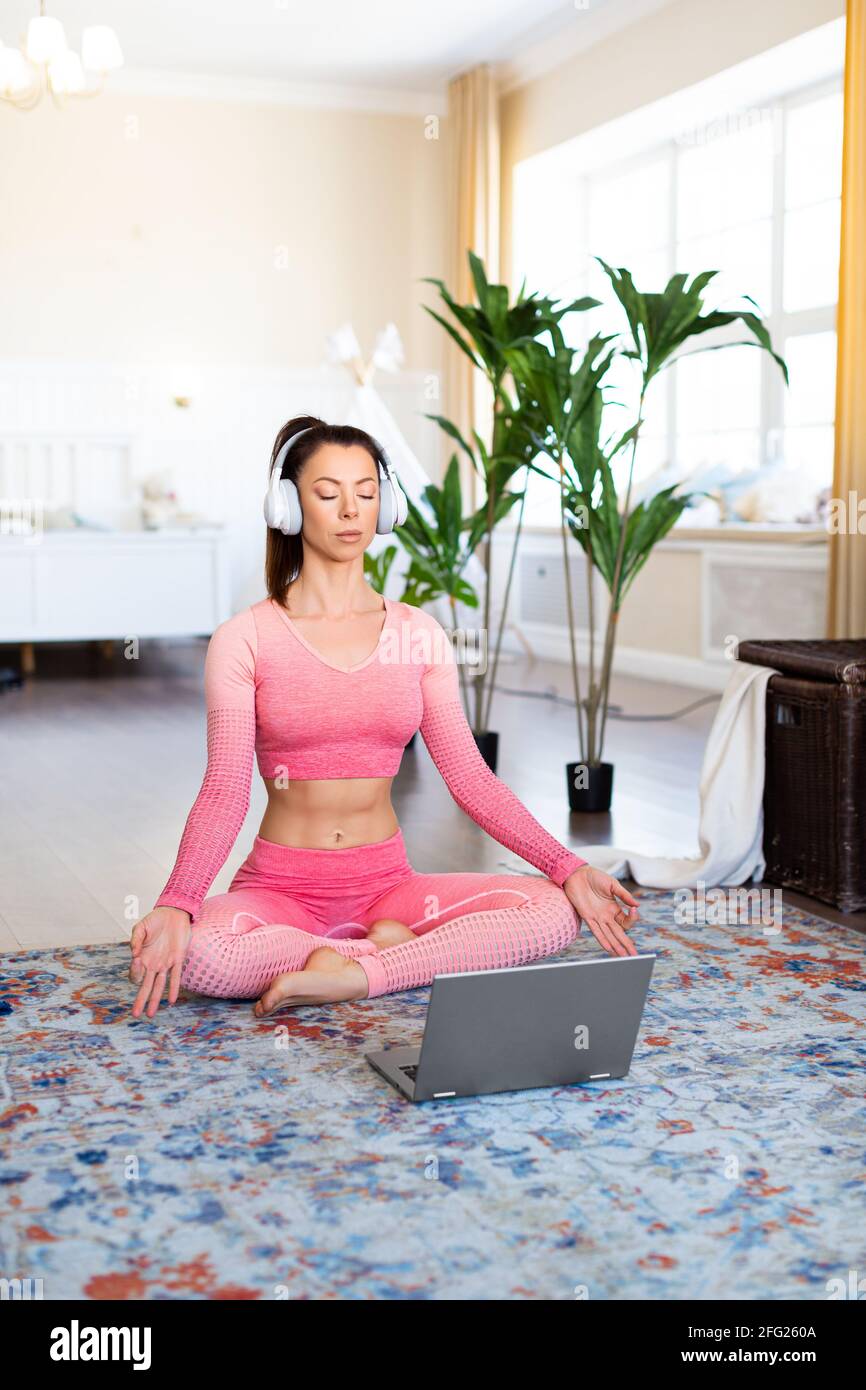 Vertical photo of a woman meditates at home in front of a laptop ...