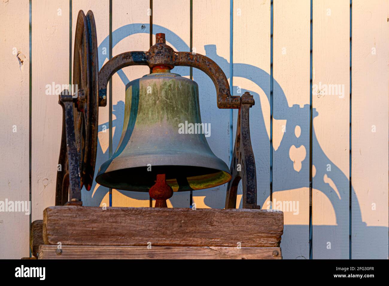 Closeup isolated image of a rusty church bell immobilized on wooden blocks through metal framing. There is an ancient wheel mechanism to operate it sy Stock Photo