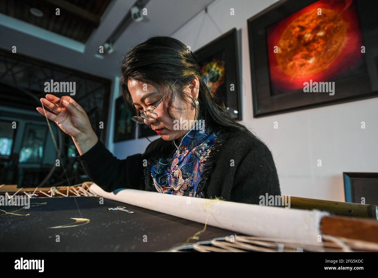 (210425) -- SUZHOU, April 25, 2021 (Xinhua) -- Chen Yinghua embroiders at her Suzhou Embroidery studio in Suzhou, east China's Jiangsu Province, April 14, 2021. Chen Yinghua, an embroidery artist, has brought her own 'universe' created with needles and silk threads, to the opening ceremony of the Space Day of China held here on Saturday. Based in Suzhou, a city with time-honored embroidery arts in east China's Jiangsu Province, Chen's studio outshines its peers with a series of cosmos-themed artworks. The dreamy celestial bodies in her studio are skillfully knitted with the help of multip Stock Photo