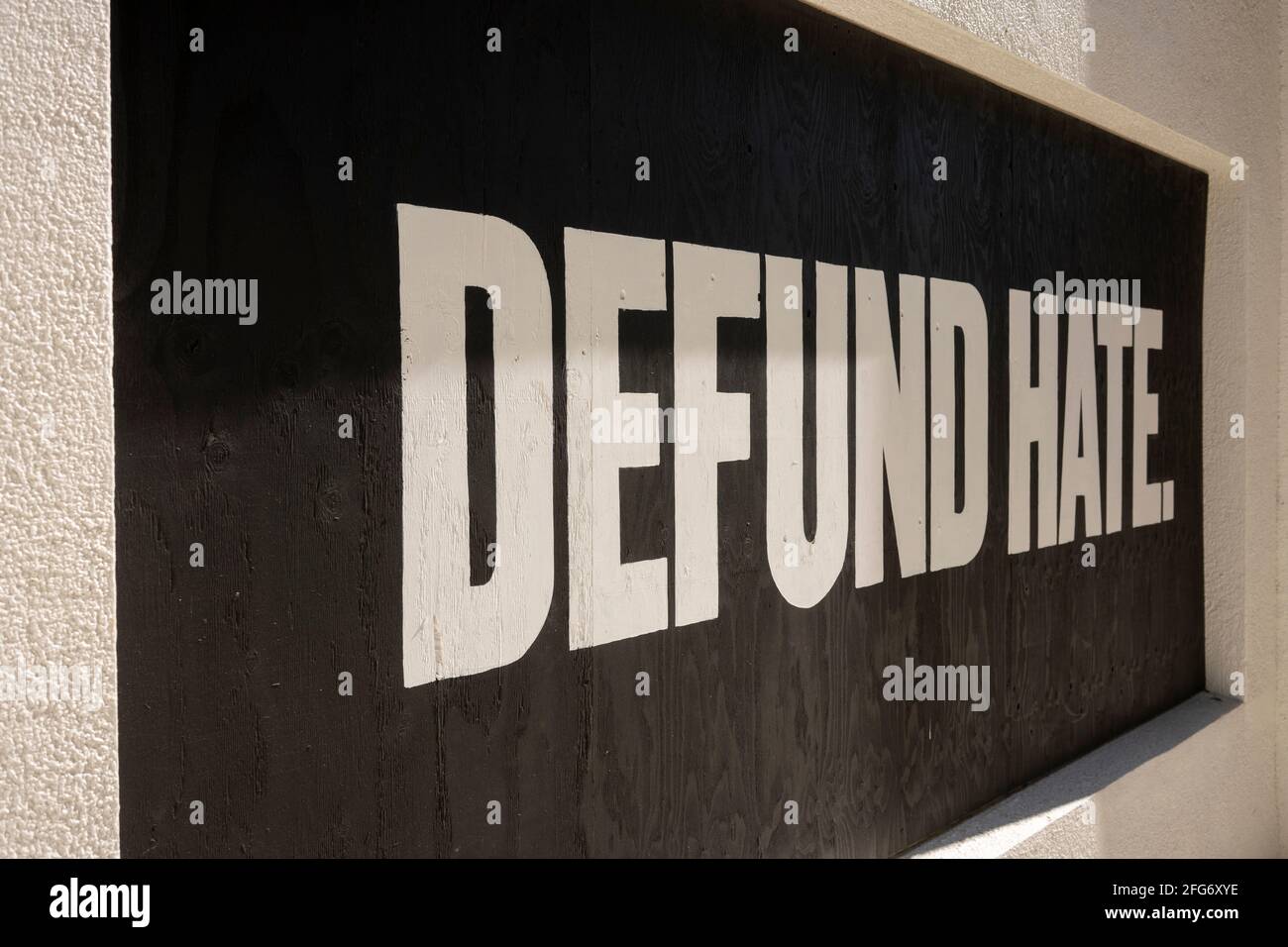 Defund Hate. Positive slogan painted on boarded-up window during protests. Stock Photo