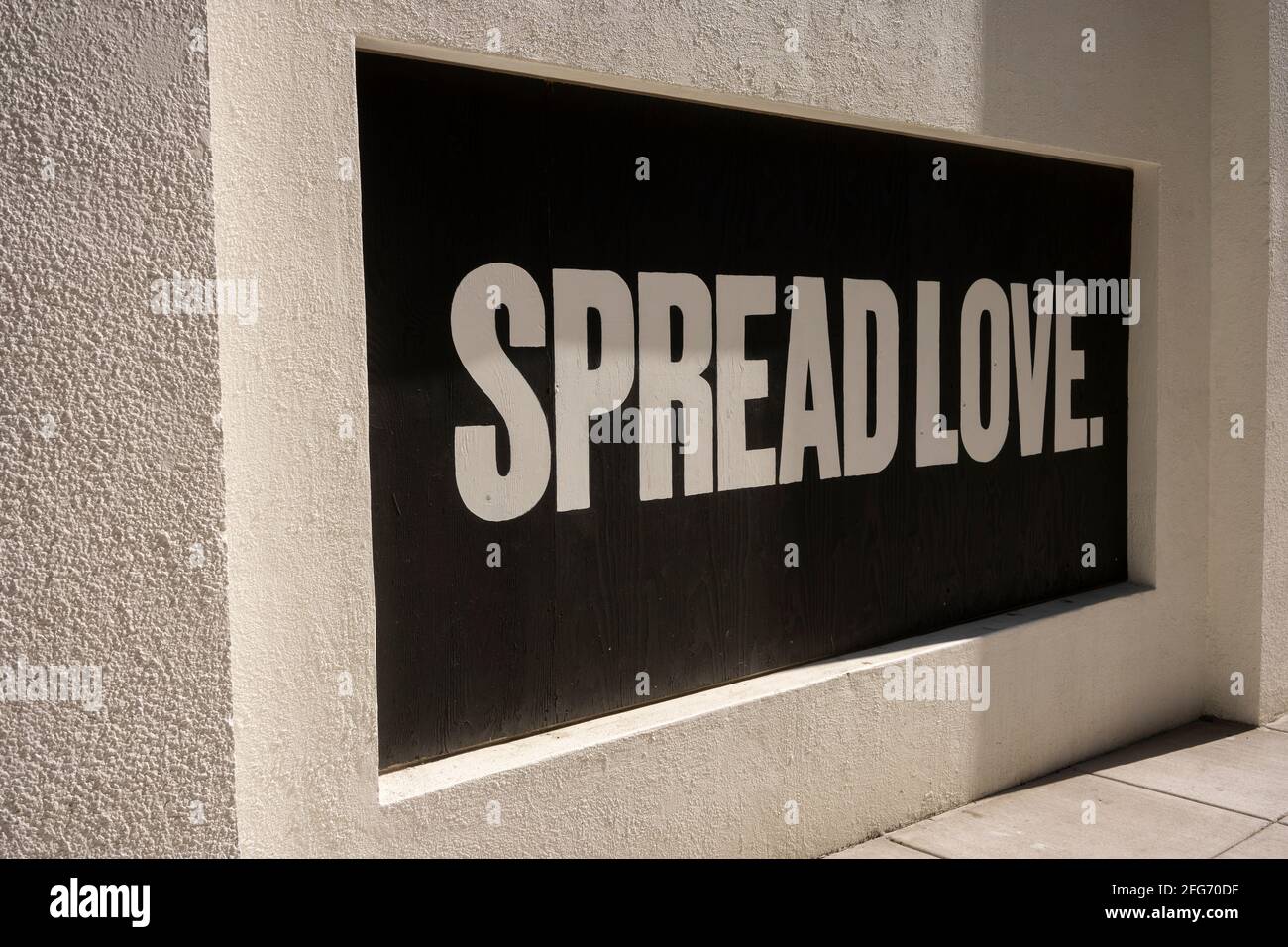 Spread Love. Positive slogan painted on boarded-up window during protests. Stock Photo