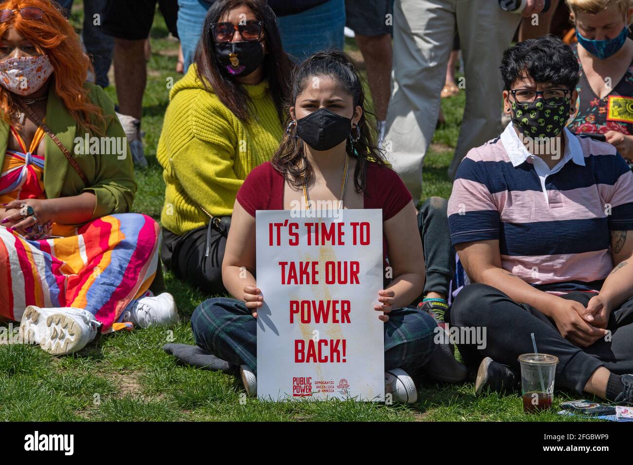 A woman holds a sign that reads 'it's time to take our power back!' during Earth Day Celebration in Astoria Park of the Queens borough of New York City.Congresswoman Ocasio-Cortez joined by New York State Senator Jessica Ramos and New York Assembly Member Zohran Mamdani for remarks about the NRG Energy, Inc proposal for the Astoria power plant. The Congresswoman opposes NRG's effort to replace their 50-year old turbine at the Astoria 'peaker' plant with a generator that burns fossil fuels extracted by fracking. Stock Photo