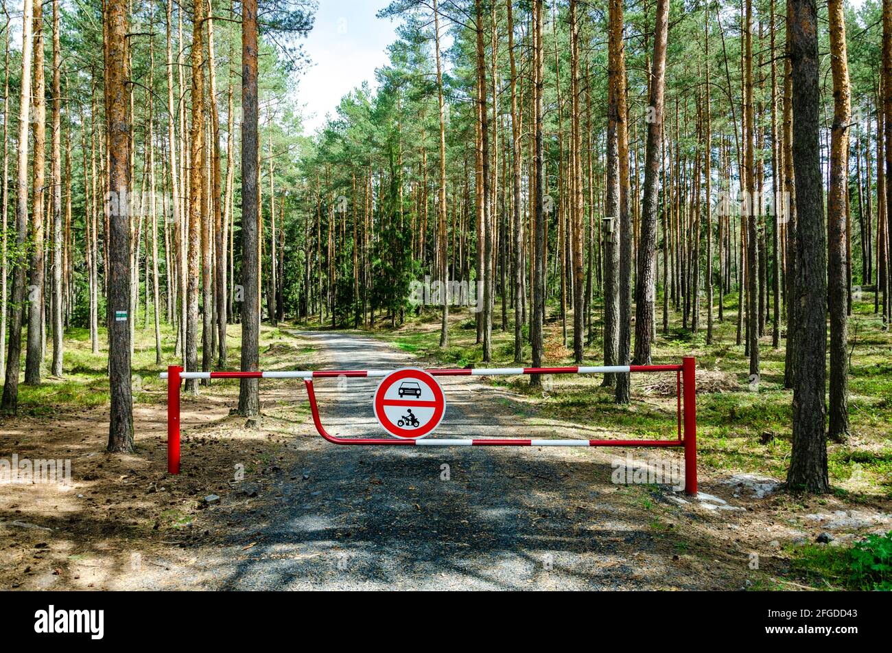 Red and white traffic barrier with road sign „no entry“ for stopping cars and motorbikes to enter into the wood Stock Photo