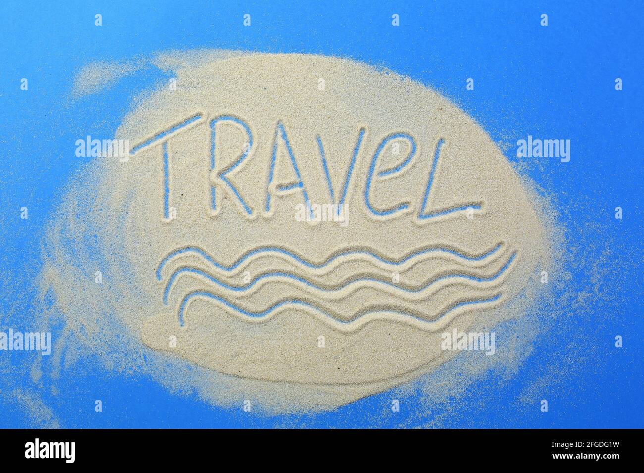 the-word-travel-is-written-in-the-sand-on-a-blue-background-stock-photo