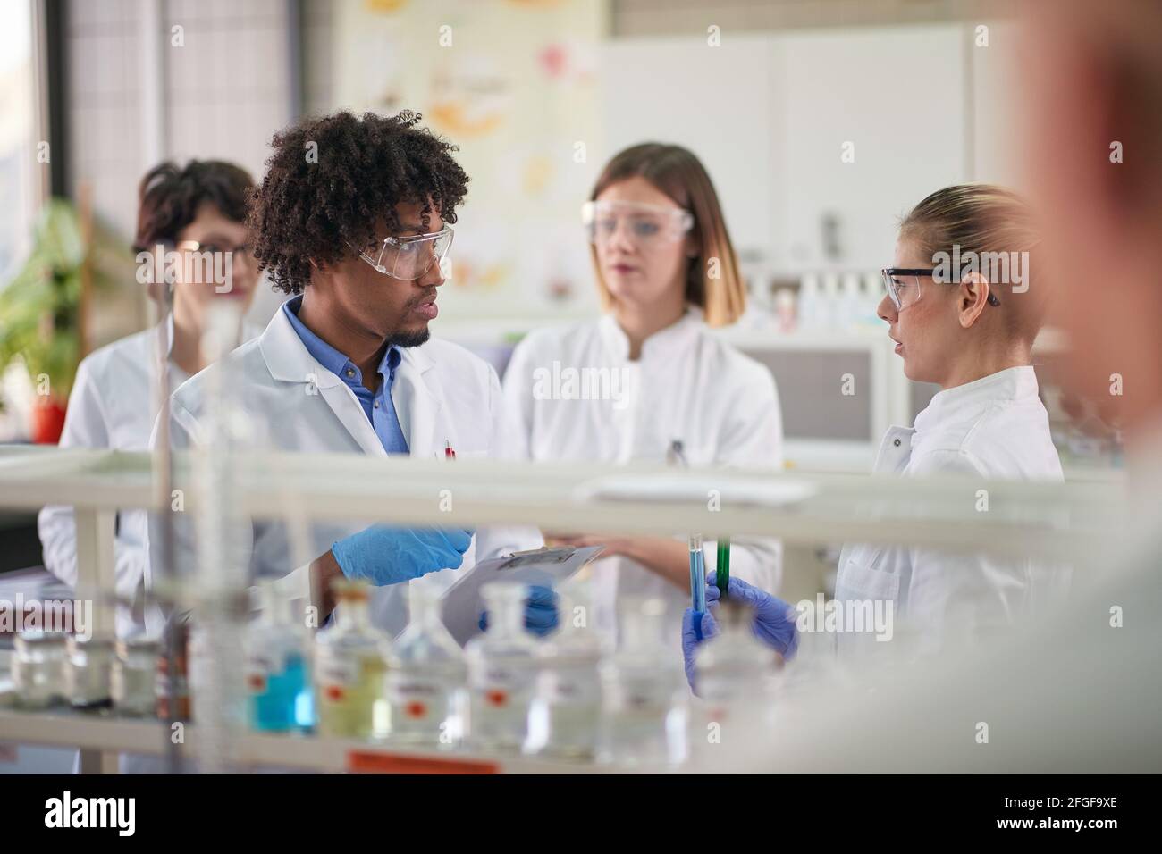 Young students discussing about the experiment in a sterile environment of the laboratory. Science, chemicals, lab, people Stock Photo