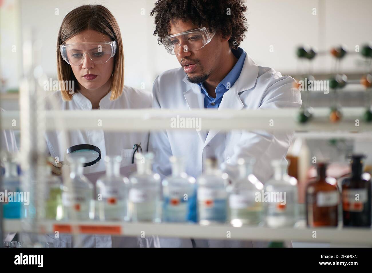 Young students working with a caution with dangerous chemicals in a sterile laboratory enviroment. Science, chemistry, lab, people Stock Photo