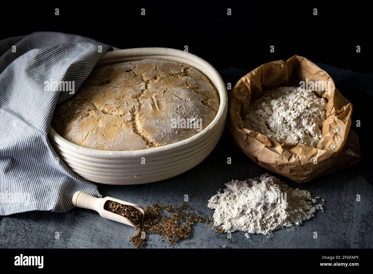 Sourdough bread rising in a wooden basket arranged with flour and cumin