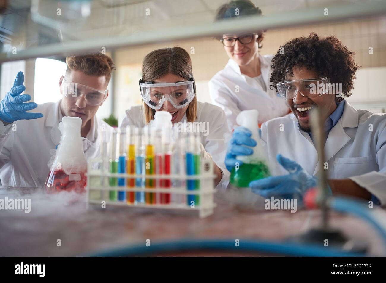 Young chemistry students in a laboratory relaxed atmosphere are excited while watching colorful chemical reactions. Science, chemistry, lab, people Stock Photo