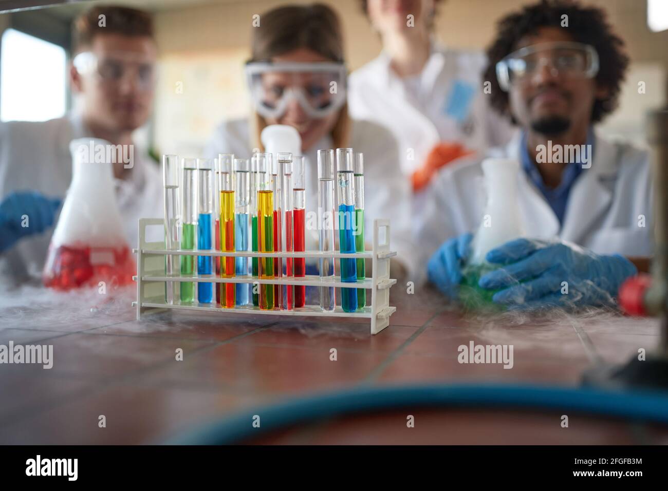 Young chemistry students in a sterile laboratory environment are enjoying observing colorful chemical reactions. Science, chemistry, lab, people Stock Photo
