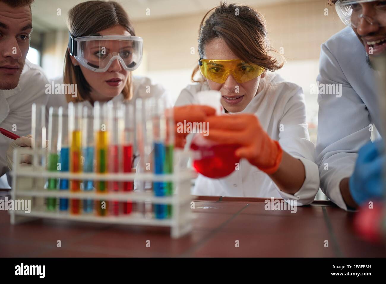 Young chemistry students in a cheerful atmosphere in a laboratory are watching a chemical reaction in an experiment. Science, chemistry, lab, people Stock Photo