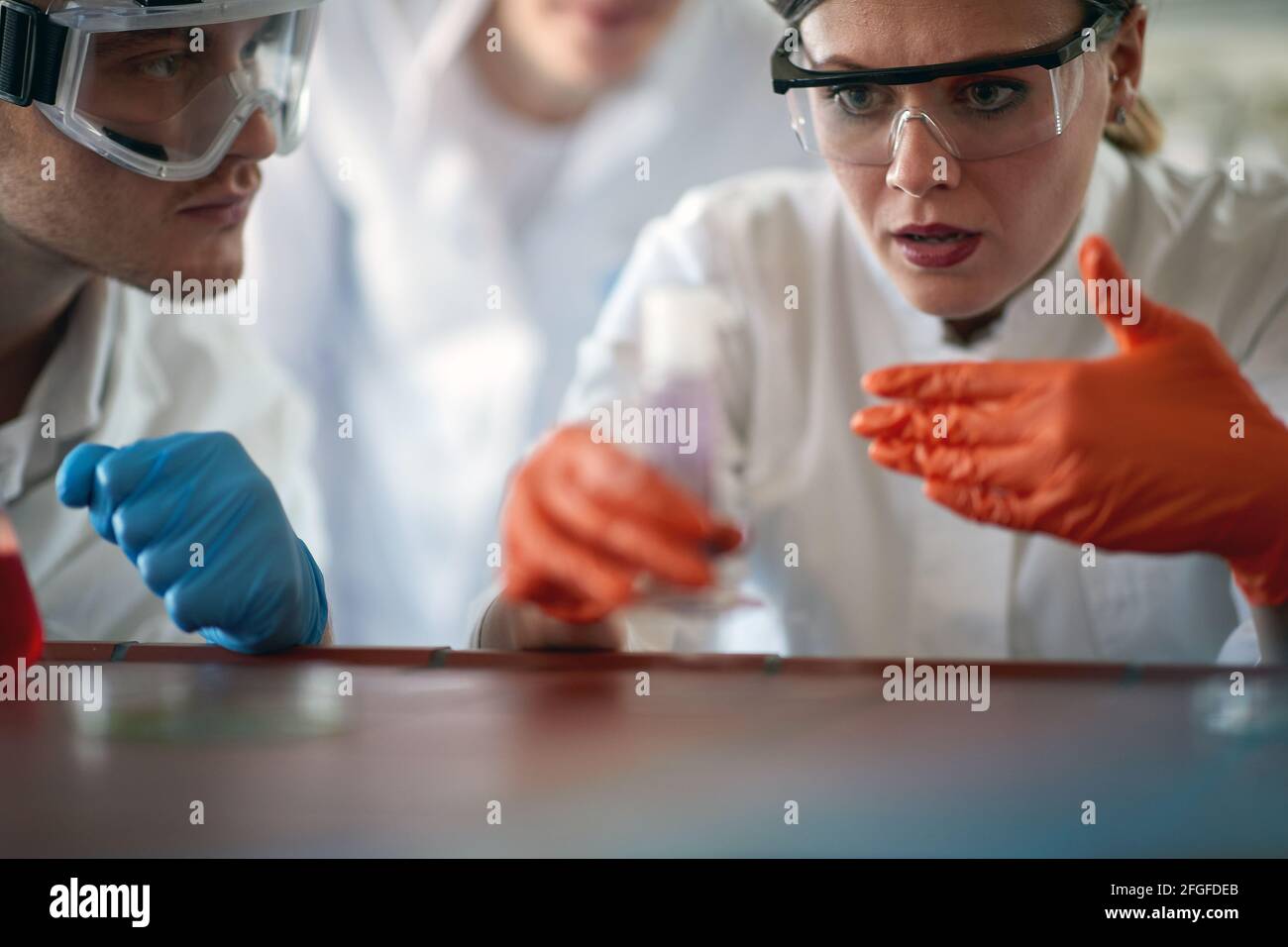 Young chemistry students in a protective gear work with dangerous chemicals in a working atmosphere in the university laboratory. Science, chemistry, Stock Photo