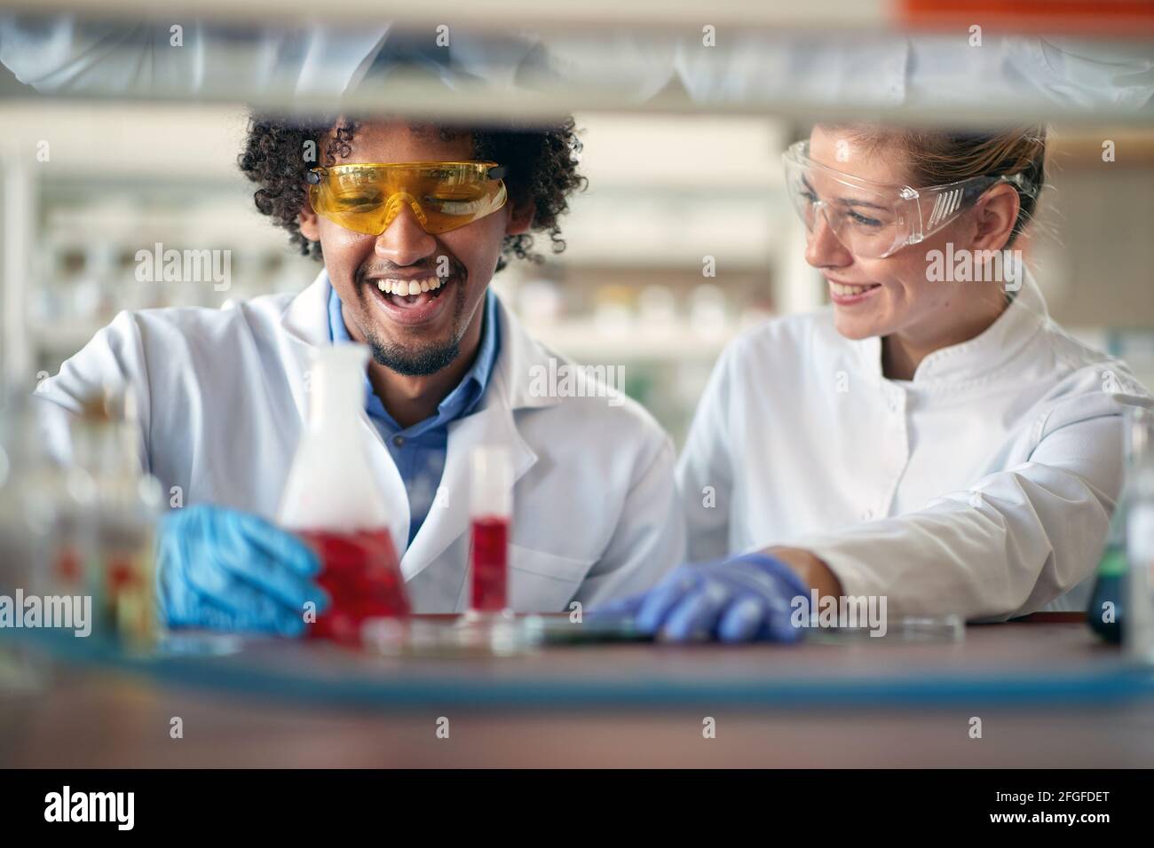 Young chemistry students in a protective gear work with a pleasure in a relaxed atmosphere in the university laboratory. Science, chemistry, lab, peop Stock Photo