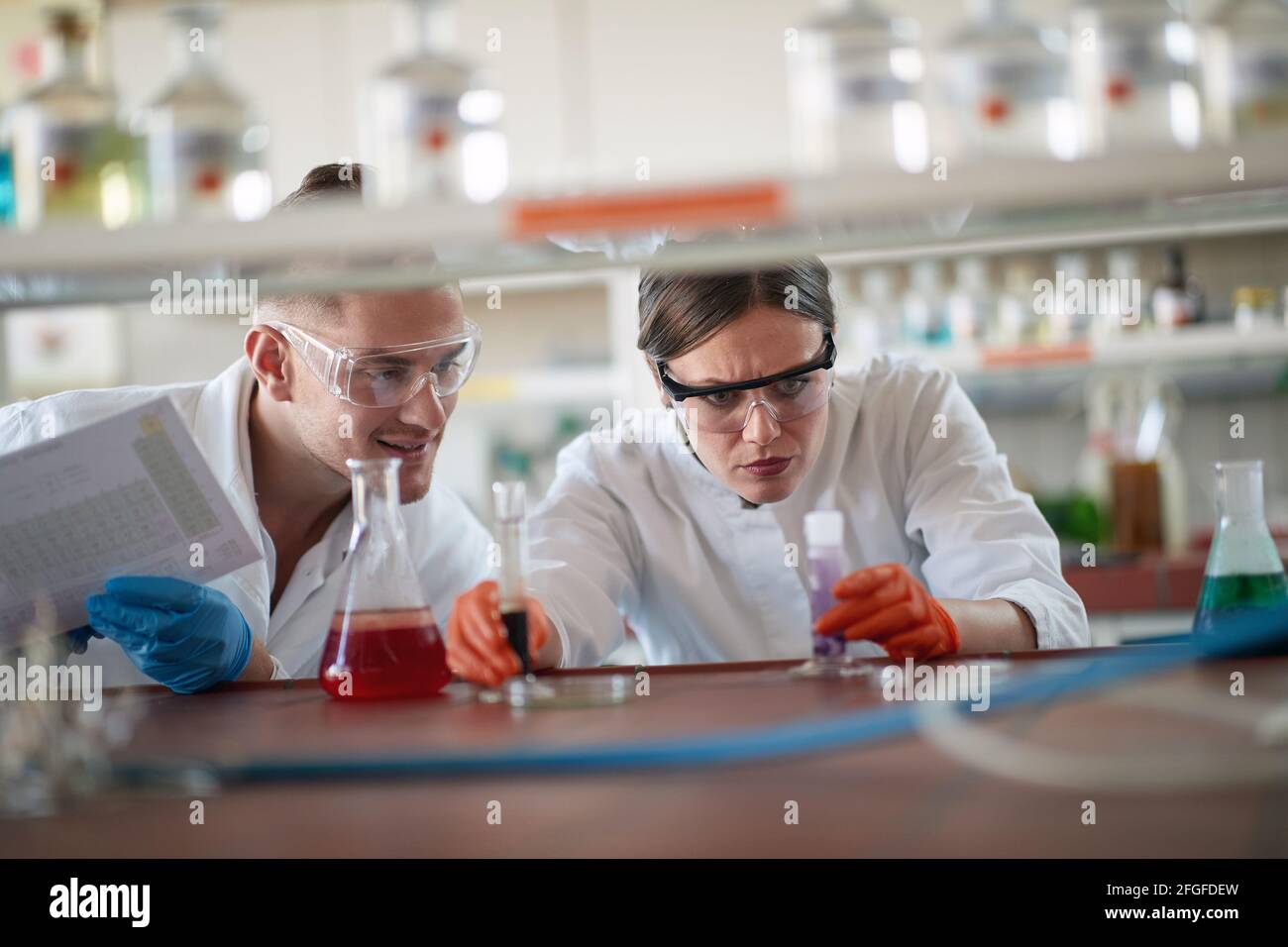 Young chemistry students in a protective gear analyze chemical reaction in a working atmosphere in the university laboratory. Science, chemistry, lab, Stock Photo