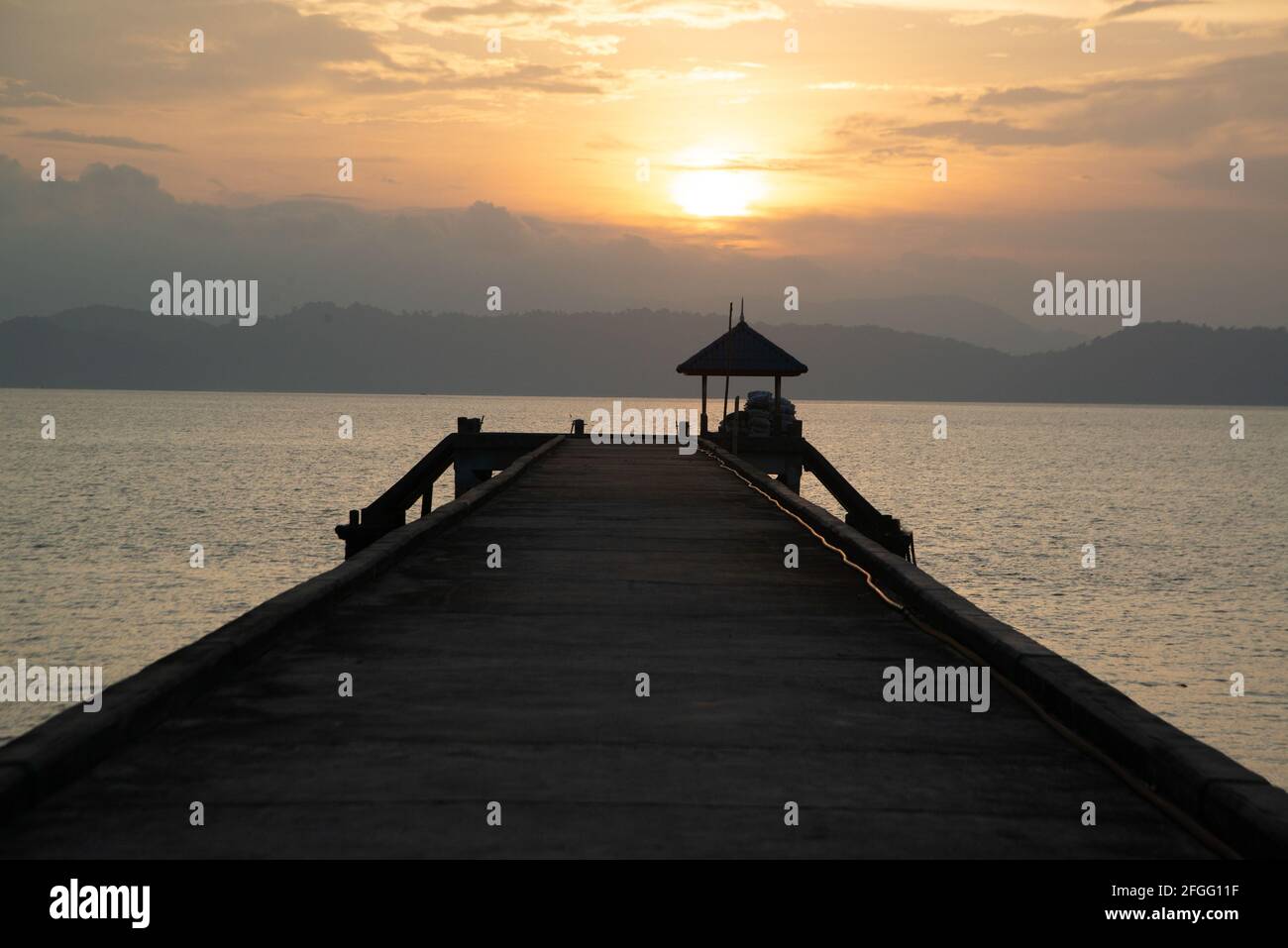 Silhouette of concrete bridge extends into the sea on a cloudy day in ...