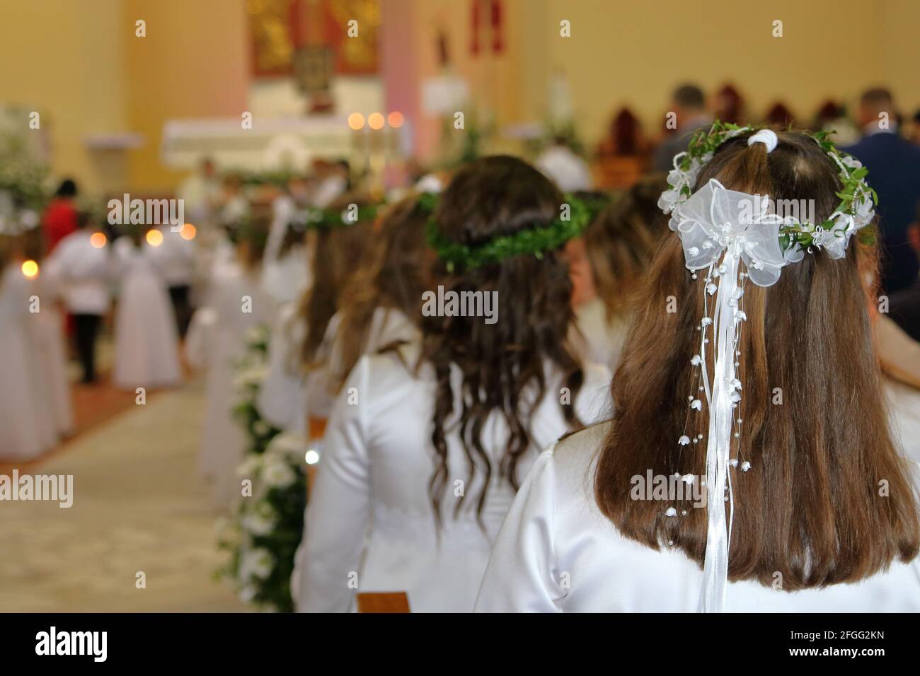 Celebration of Fistt Holy Communion in Catholic church, Poland, girls in white dresses, wreath, inside church during holy mass Stock Photo