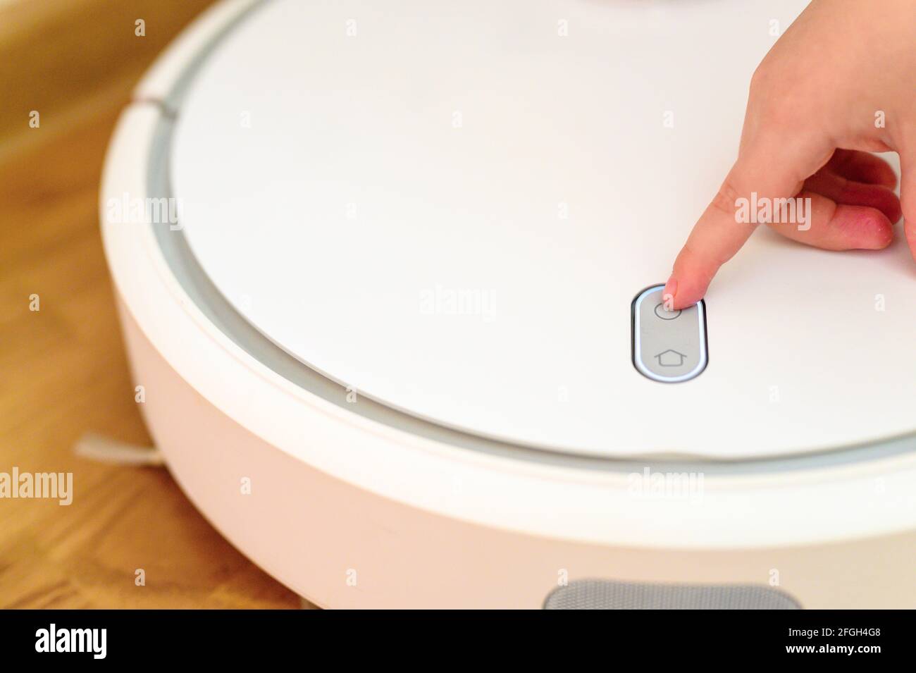 a kids hand presses the button to turn the robot vacuum cleaner on